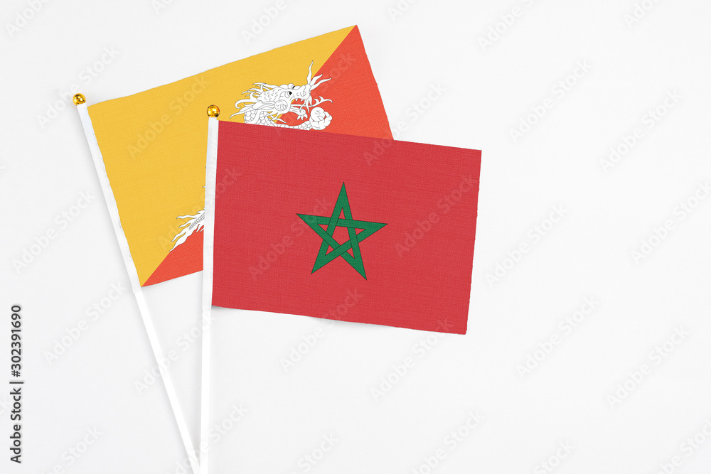 Morocco and Bhutan stick flags on white background. High quality fabric, miniature national flag. Peaceful global concept.White floor for copy space. Morocco and Bhutan stick flags on white background. High quality fabric, miniature national flag. Peaceful global concept.White floor for copy space.