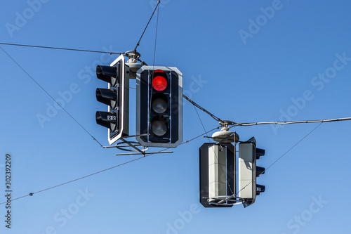 Red stop light on traffic light sign, hanging on wires.