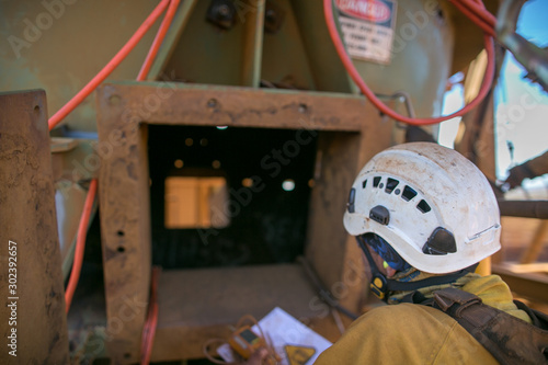 Certifies miner wearing fall body harness helmet protection holding gas test detector confined space permit book and inspecting safety environment surrounding before conduct gas testing prior entry photo