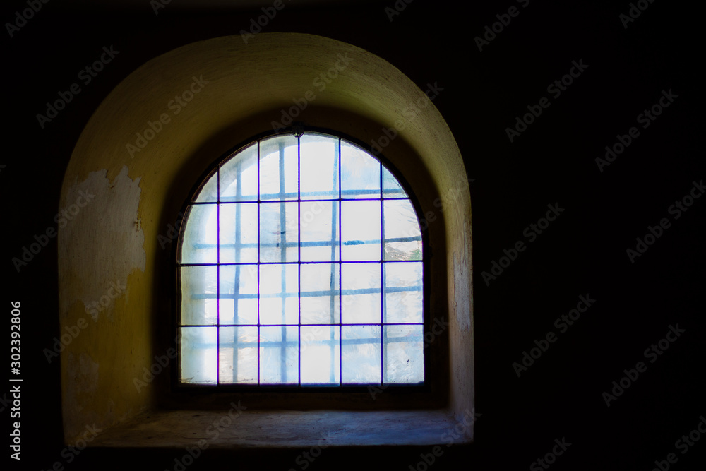 Castle prison window from darkness with stained glass and bars