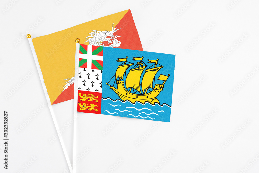 Saint Pierre And Miquelon and Bhutan stick flags on white background. High quality fabric, miniature national flag. Peaceful global concept.White floor for copy space. Saint Pierre And Miquelon and Bhutan stick flags on white background. High quality fabric, miniature national flag. Peaceful global concept.White floor for copy space.