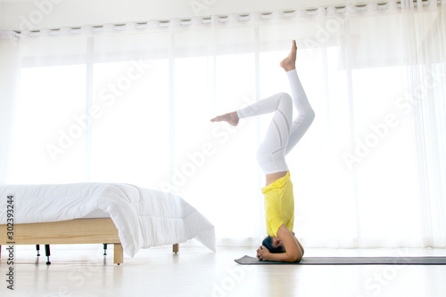 Skinny woman wear yellow sport t-shirt practice yoga exercises for relaxing in the bedroom near the window, healthy lifestyle concept.
