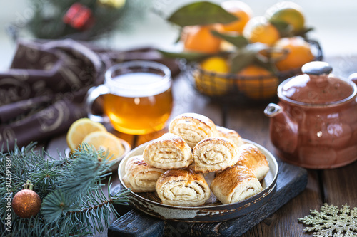 Oriental dessert gata with a cup of tea and tangerines on a wooden table. Selective focus photo