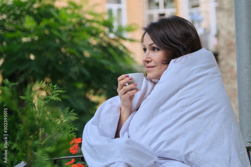 Smiling happy middle-aged woman with cup of coffee dressed in blanket Smiling happy middle-aged woman with cup of coffee dressed in blanket