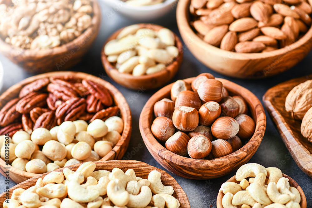 A variety of nuts in wooden bowls from top view. Walnuts, cashew, almond, pistachio, pecan, hazelnut, macadamia nut. Healthy super food selection. A variety of nuts in wooden bowls from top view. Walnuts, cashew, almond, pistachio, pecan, hazelnut, macadamia nut. Healthy super food selection.