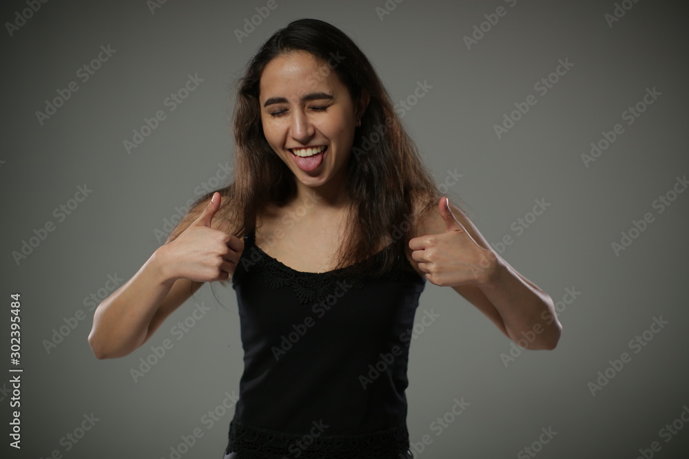 The perky girl has fun and shows her tongue raising both hands The perky girl has fun and shows her tongue raising both hands