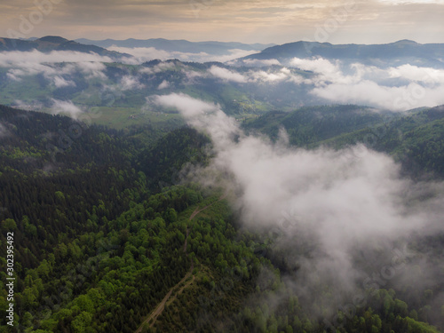 Aerial view of mist, cloud and fog hanging over a lush rain forest after a storm