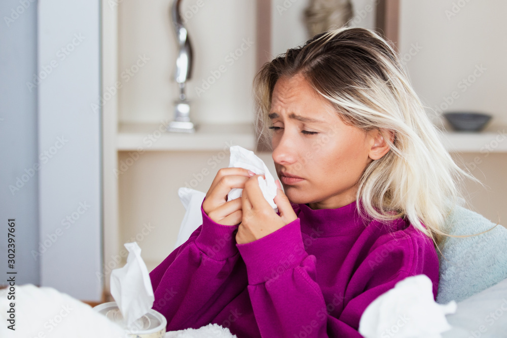Sick Woman.Flu.Woman Caught Cold. Sneezing into Tissue. Headache. Virus .Medicines. Young Woman Infected With Cold Blowing Her Nose In Handkerchief. Sick woman with a headache sitting on a sofa Sick Woman.Flu.Woman Caught Cold. Sneezing into Tissue. Headache. Virus .Medicines. Young Woman Infected With Cold Blowing Her Nose In Handkerchief. Sick woman with a headache sitting on a sofa