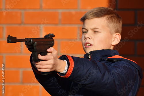 Child with dangerous weapons. Boy shoots gun. Teenager with a gun. Child learn to shoot.