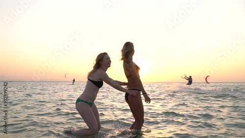 Young ladies are dancing in the sea, enjoying the sunset, beach party