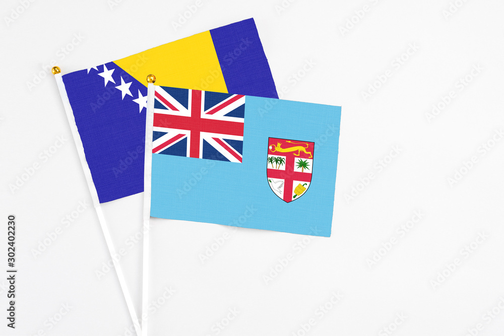 Fototapeta premium Fiji and Bosnia Herzegovina stick flags on white background. High quality fabric, miniature national flag. Peaceful global concept.White floor for copy space.