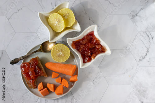 Homemade carrot jam with lemon  sugar and vanilla. In a saucer on a light background. Healthy dessert