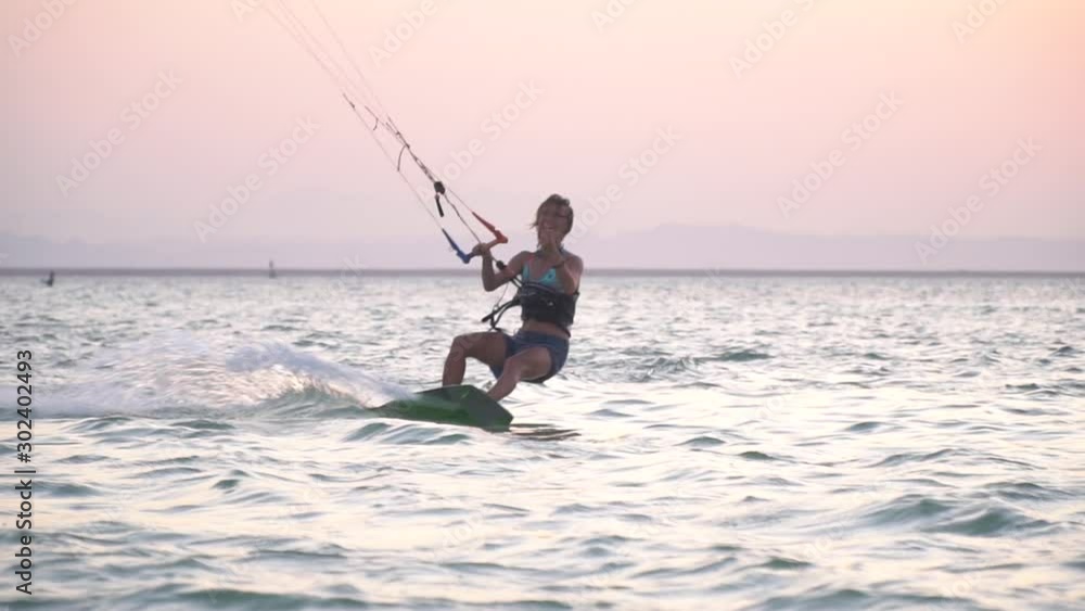 Smiling and laughing woman is kitesurfing in the sea, gliding and tilting Smiling and laughing woman is kitesurfing in the sea, gliding and tilting