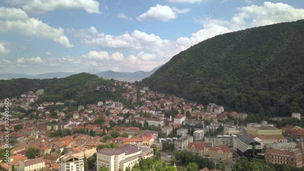 Aerial view of Brasov city, medieval town situated in Transylvania, Romania. Old architecture surrounded with big Carpathian mountains covered with dense green forest. Aerial view of Brasov city, medieval town situated in Transylvania, Romania. Old architecture surrounded with big Carpathian mountains covered with dense green forest.