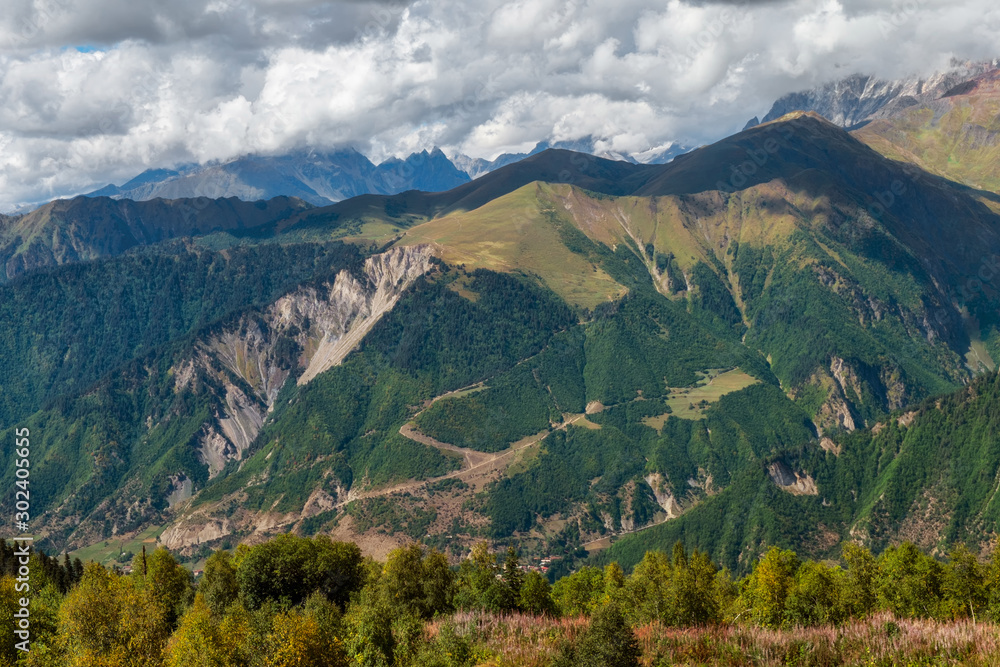 Mountains and green meadow with trees seen from Hatsvali ski resort on a sunny autumn day in Svaneti Georgia