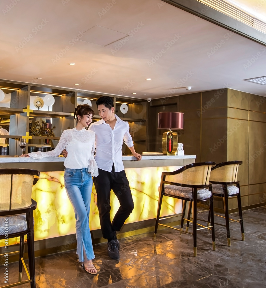 A pair of young men and women drinking at the bar counter A pair of young men and women drinking at the bar counter