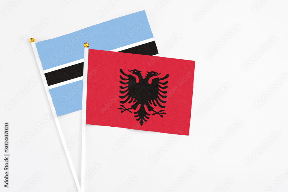 Fototapeta premium Albania and Botswana stick flags on white background. High quality fabric, miniature national flag. Peaceful global concept.White floor for copy space.