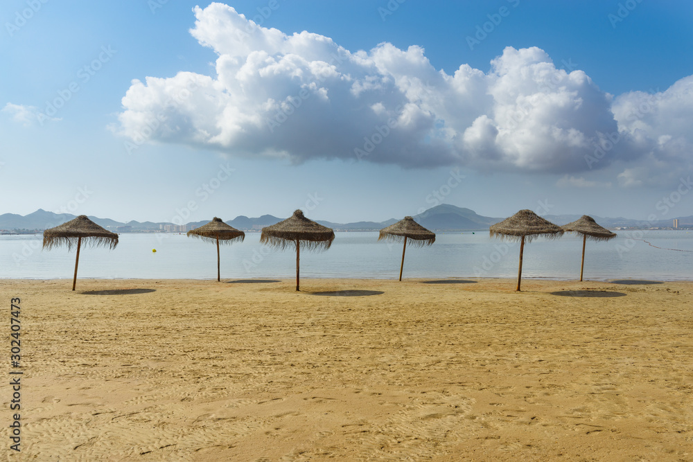 Umbrellas on the beach by the sea. La Manga del Mar Menor. Murcia, Spain