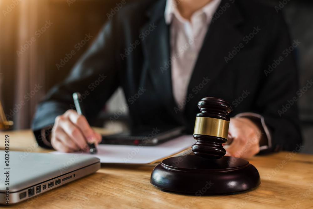 Justice and law concept. Female judge in a courtroom with the gavel working with digital tablet computer docking keyboard on wood table. Justice and law concept. Female judge in a courtroom with the gavel working with digital tablet computer docking keyboard on wood table.