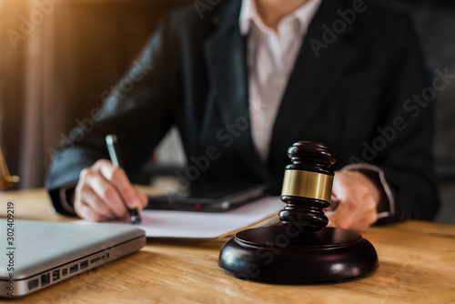 Justice and law concept. Female judge in a courtroom with the gavel working with digital tablet computer docking keyboard on wood table.