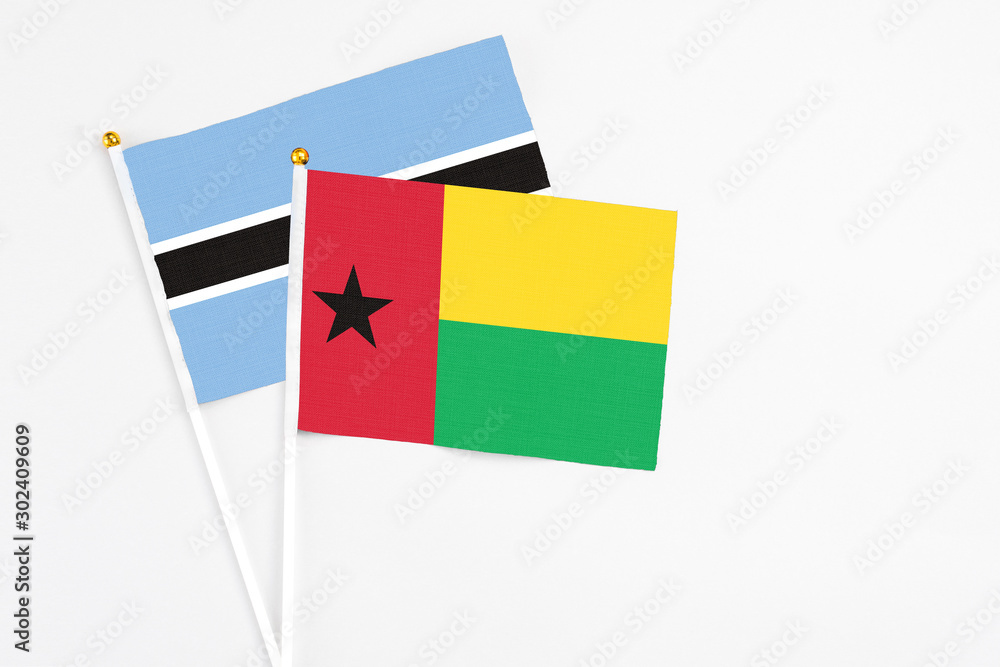 Guinea Bissau and Botswana stick flags on white background. High quality fabric, miniature national flag. Peaceful global concept.White floor for copy space.