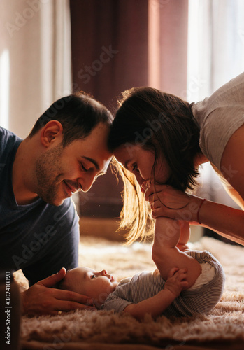 Baby with his parents playing on the bed. Happy family at home. Lifestyle cozy photos. Little boy 4 months old