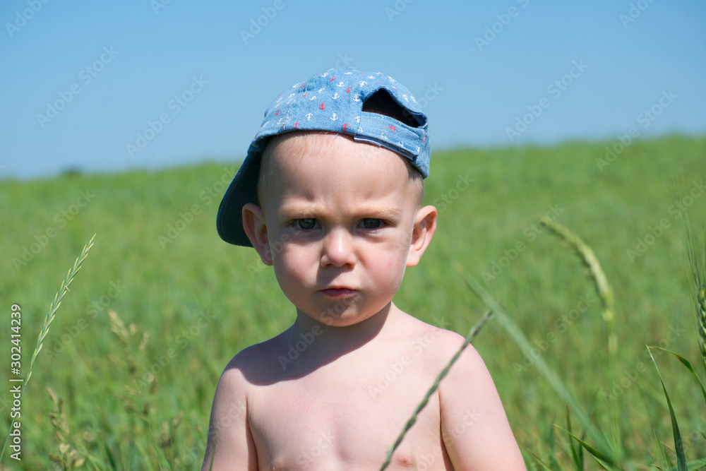 Cute blond child playing in a green meadow among tall grass