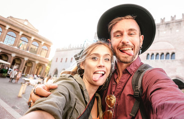 Happy boyfriend and girlfriend in love having genuine fun taking selfie at old town tour - Wanderlust life style travel vacation concept with tourist couple on city sightseeing - Bright warm filter