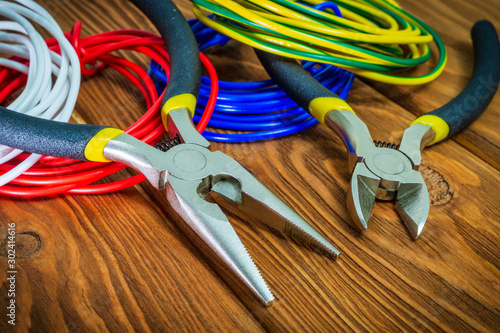 Pliers tool and wires for electrician closeup on wooden boards
