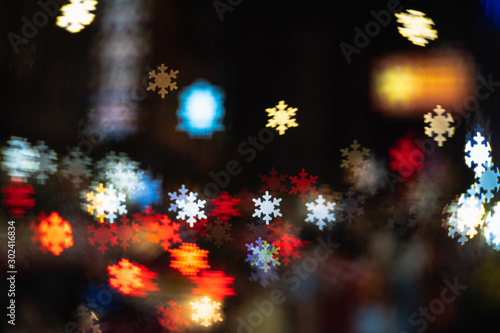 Defocused in city night street colorful rays lights with snowflakes bokeh background  Blurred dramatic glowing night lights  Abstract background for Christmas celebrate holidays banner xmas concept