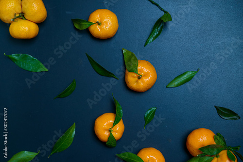 Ripe gorgeous tangerines with leaves isolated on a blue wooden background.