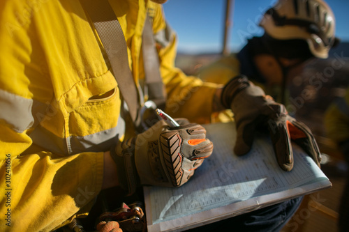Construction workers wearing a industry safety glove signing of high risk working at height permit on the opening field prior starting early day shift