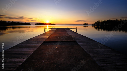 Fototapeta Naklejka Na Ścianę i Meble -  A large jetty leading out into a lake with sunset in the background