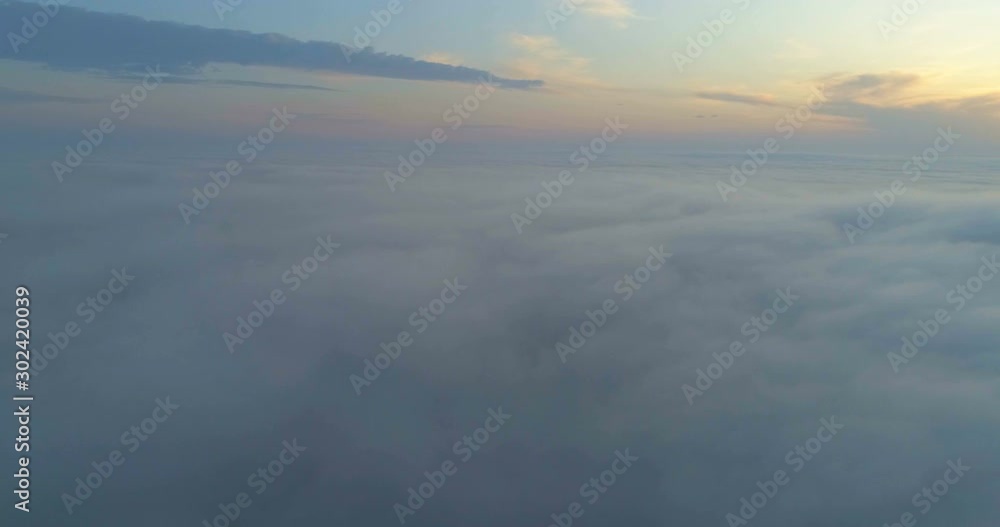 Drone flying over the clouds at sunset. The sun is hidden behind the clouds at sunset fog. Drone flying over the clouds at sunset. The sun is hidden behind the clouds at sunset fog.
