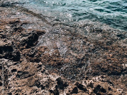 Rocks and water. Abstract sea background. Beautiful texture with a rocky sea coast in summer.