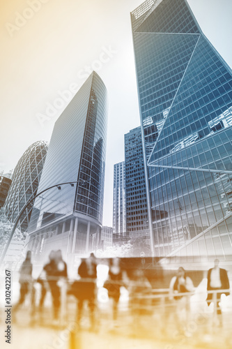 Silhouettes of people walking in the street near skyscrapers and modern office buildings in Paris business district. Multiple exposure image. Economy, finances, business concept illustration.