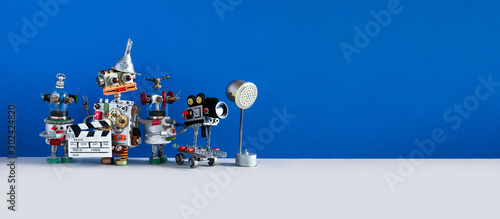 Comical robotic art filmmaking process. Backstage TV production studio with funny director cameraman and assistant. Shoots blockbuster television or movie. Copy space on blue gray backdrop