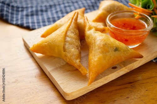 Samosas on wooden board.