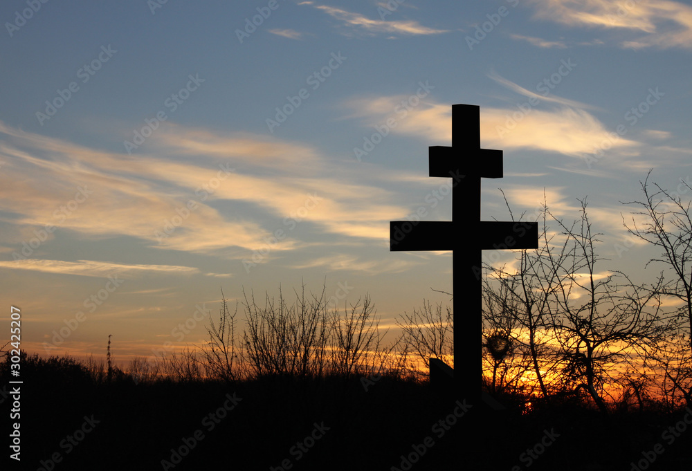 Christian cross on blue sky background at sunset