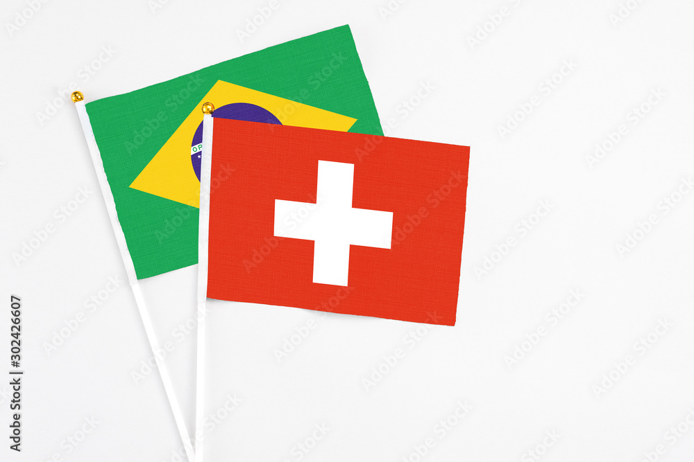 Obraz premium Switzerland and Brazil stick flags on white background. High quality fabric, miniature national flag. Peaceful global concept.White floor for copy space.