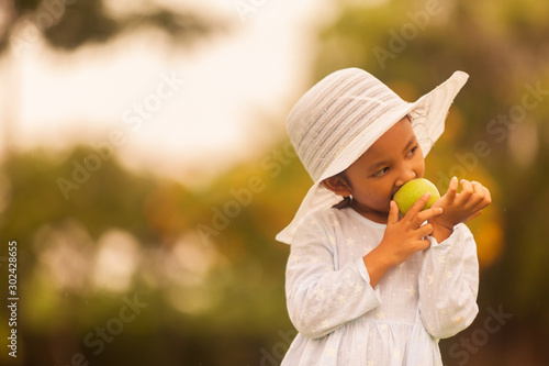 beautiful children in a hat eats an apple on nature