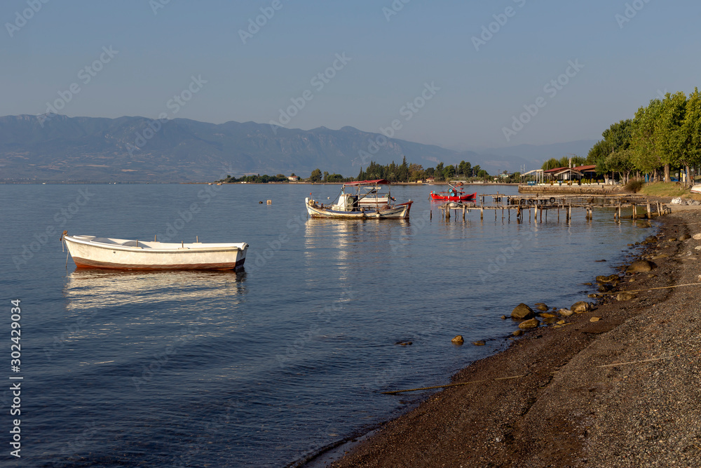 The fishing boats is moored near the shore and wooden, old pier close-up (Greece)