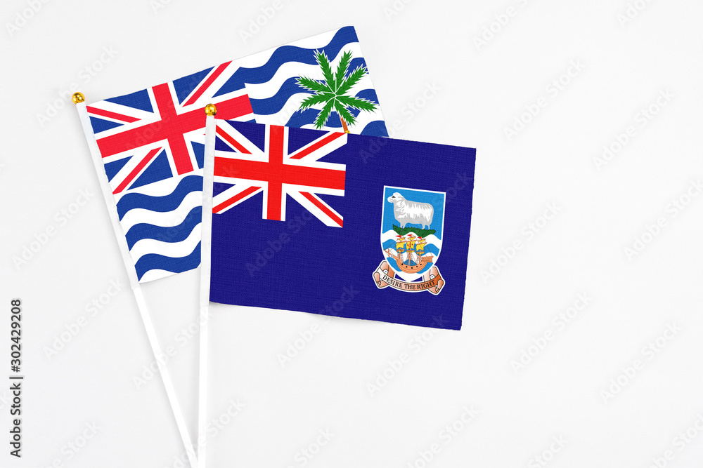 Fototapeta premium Falkland Islands and British Indian Ocean Territory stick flags on white background. High quality fabric, miniature national flag. Peaceful global concept.White floor for copy space.