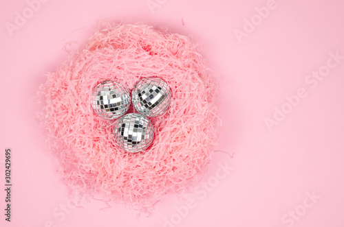 Fototapeta Naklejka Na Ścianę i Meble -  Closeup flat lay pink paper filler nest shape with silver glass Christmas balls on a pink background. Top view frame female winter holidays concept