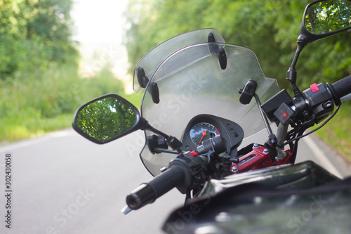 Driver riding motorcycle on an asphalt road through forest.