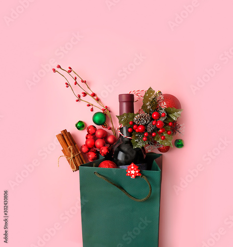 Christmas Sale bag. bottle wine, festive decor and gift in shopping bag on pink background. Winter holiday season, Christmas sale, Shopping time concept. top view