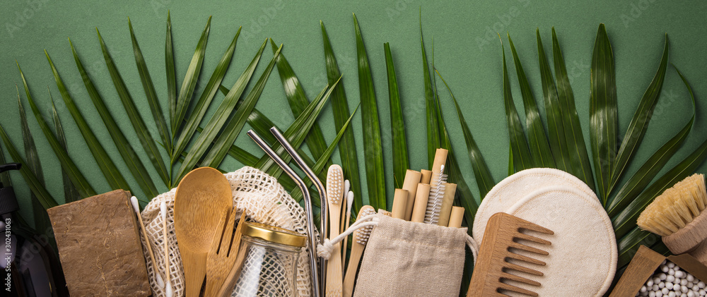 Fototapeta Koncepcja zero odpadów. Bawełniana torba, bambusowa ceramika, szklany słoik, bambusowe szczoteczki do zębów, szczotka do włosów i słomki na zielonym tle