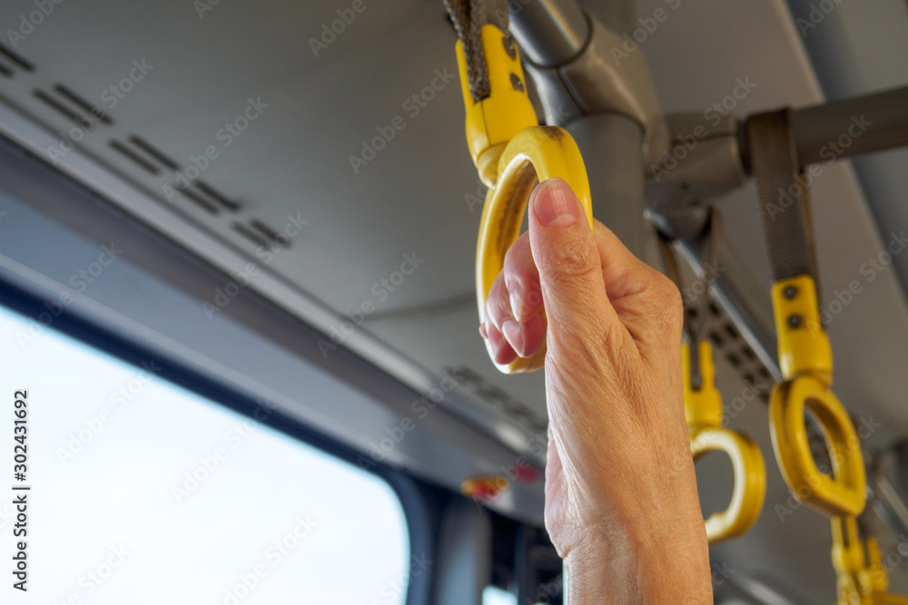 Close-up view of hand holding yellow handle in public transport. Copy space for text Close-up view of hand holding yellow handle in public transport. Copy space for text
