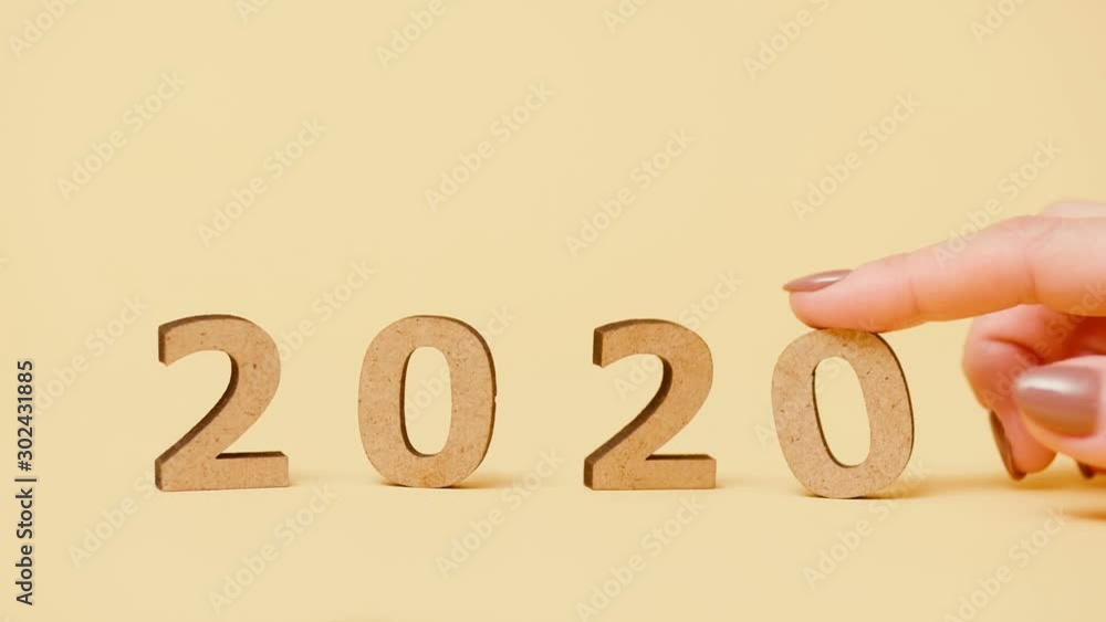 female hand puts numbers 2020 new year instead of the old 2019 by finger, wooden figures on colored background, concept change of years slow motion, creative ides female hand puts numbers 2020 new year instead of the old 2019 by finger, wooden figures on colored background, concept change of years slow motion, creative ides