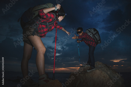 Help the hiker get help with climbing with a smile, overcoming happy obstacles. Backpacking tourists walking the rocks Young lovers hiking climbing camping concept.